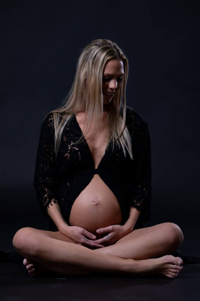 Gravid fotografering Fyn i studie, siddende gravid kvinde med smuk gravid mave, fotografering af gravid hos newbornfoto.dk
